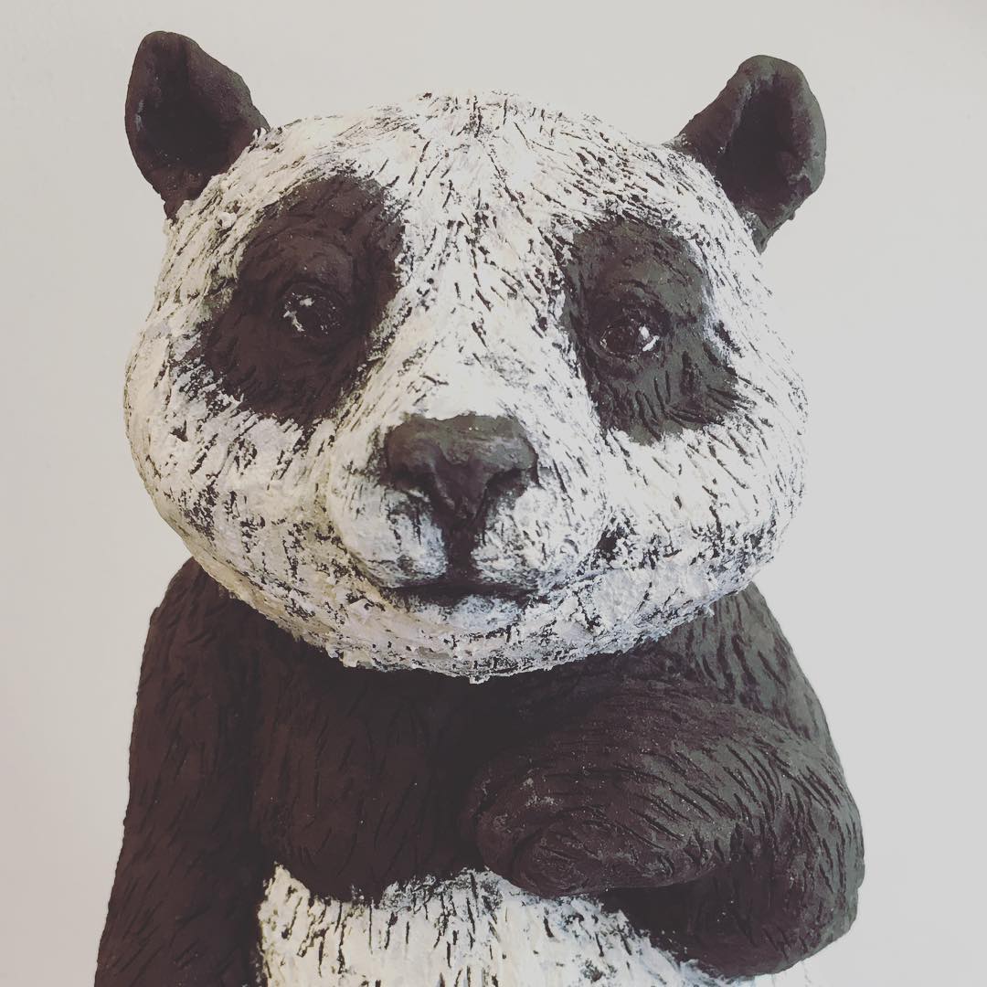 A clay sculpture of a black and white panda